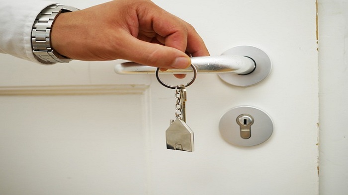 une main tenant une clé devant une porte - adresse de domiciliation - activsolutions